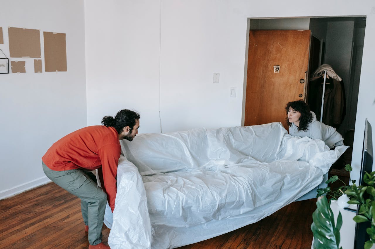 home-services-004 A couple collaboratively lifting a couch while moving into a new apartment.