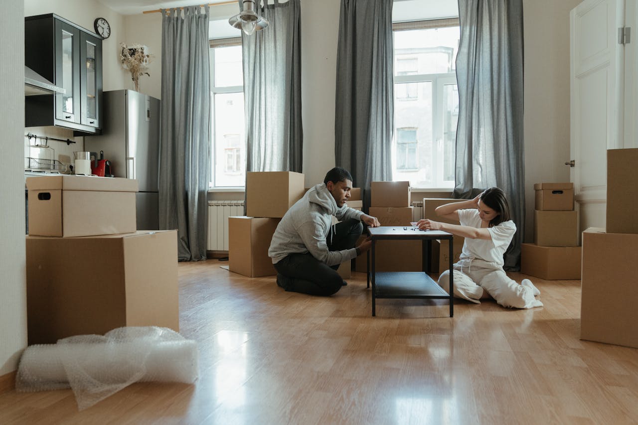 home-services-01 Young couple assembling furniture in their new apartment, surrounded by cardboard boxes.